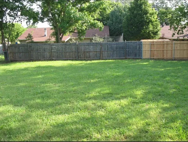 a view of a yard with a fence and trees