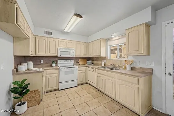 a kitchen with white cabinets stainless steel appliances a sink and a window