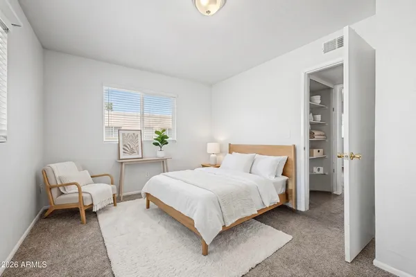 a bedroom with a bed and a lamp on dresser