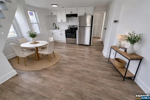 a living room with furniture a mirror and a dining table with wooden floor