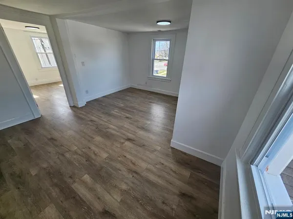 a view of empty room with window and wooden floor