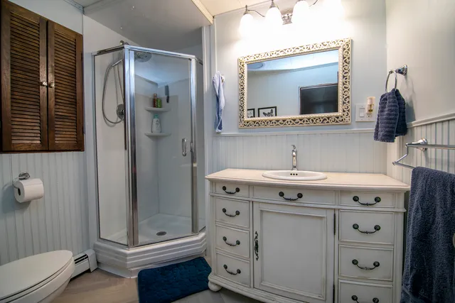 a bathroom with a sink vanity granite toilet and a mirror