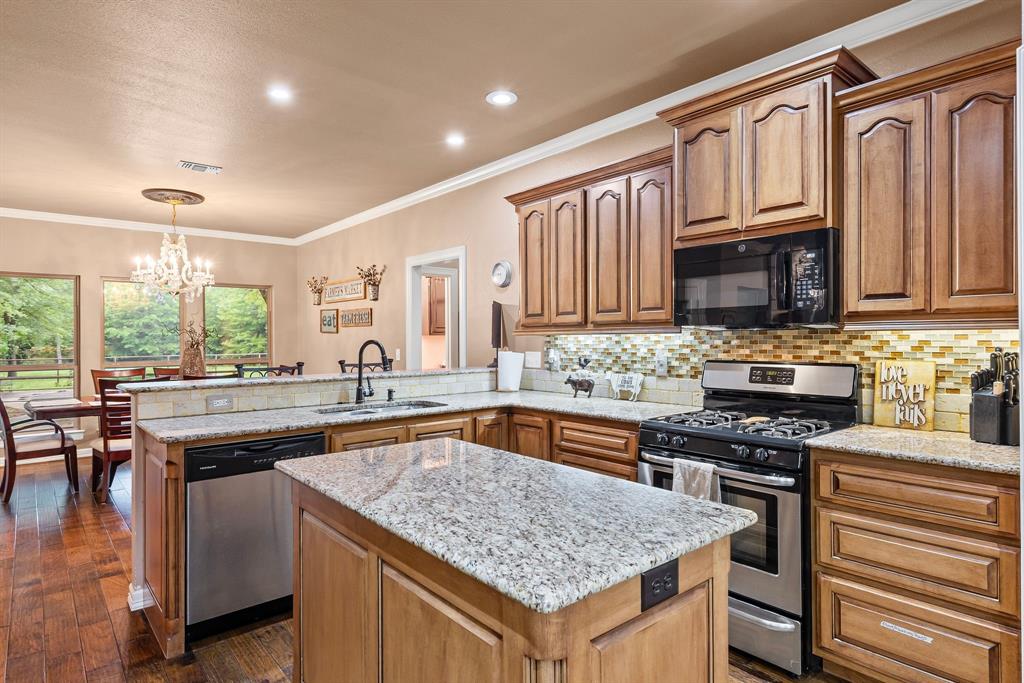 690 County Road Paris, TX 75462 - Photo 13 of 40 a kitchen with stainless steel appliances granite countertop a stove top oven a sink dishwasher and microwave with wooden floor