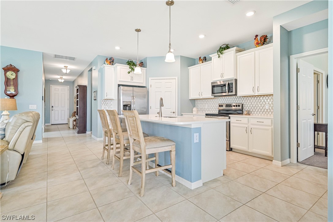 3435 Gold Flower Street Fort Myers, FL 33905 - Photo 20 of 39 a kitchen with kitchen island stainless steel appliances a table chairs sink and cabinets