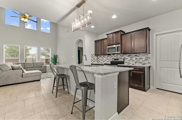 a kitchen with kitchen island granite countertop a stove a sink a oven with a dining table and chairs