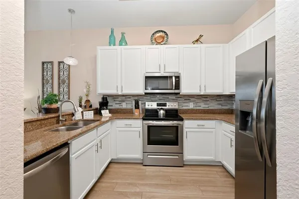 a kitchen with a sink stainless steel appliances and white cabinets