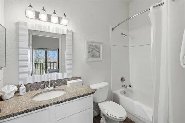 a bathroom with a granite countertop sink toilet a mirror and shower