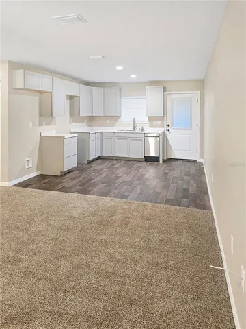 a large white kitchen with kitchen island white cabinets and wooden floor