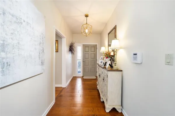 a view of a hallway with wooden floor windows and a chandelier