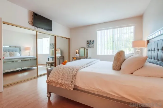 a spacious bedroom with a bed and glass walk in closet