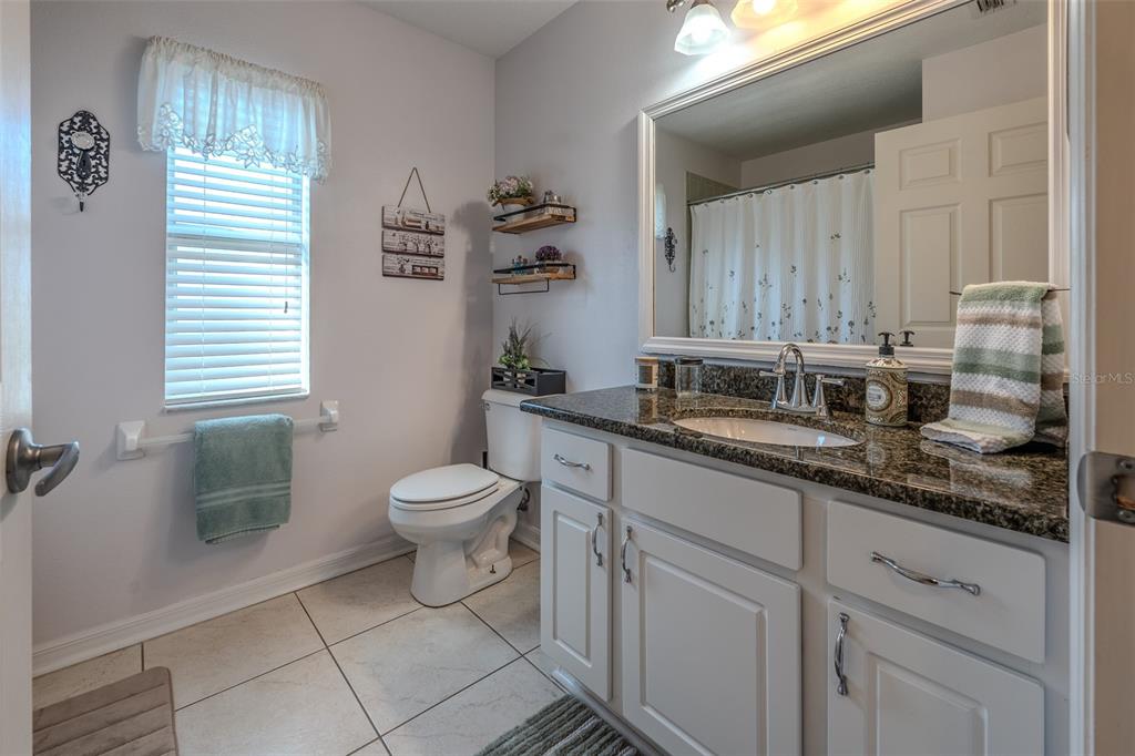 15143 Southwest 14th Avenue Road Ocala, FL 34473 - Photo 29 of 53 a bathroom with a granite countertop sink a toilet and a mirror