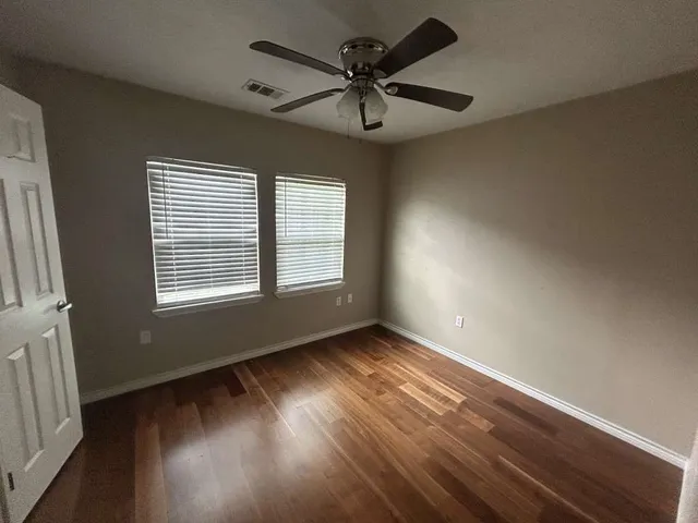 a view of an empty room with a window and wooden floor