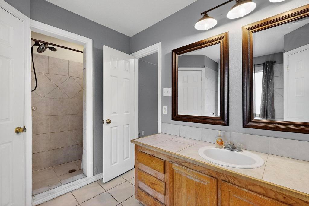 109 Pleasant Run Azle, TX 76020 - Photo 22 of 40 a bathroom with a granite countertop sink mirror and shower