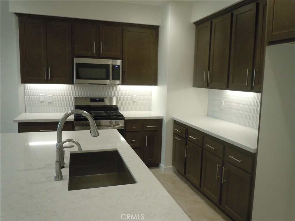 32402 Brunello Way Temecula, CA 92591 - Photo 11 of 22 a kitchen with a sink a stove and cabinets