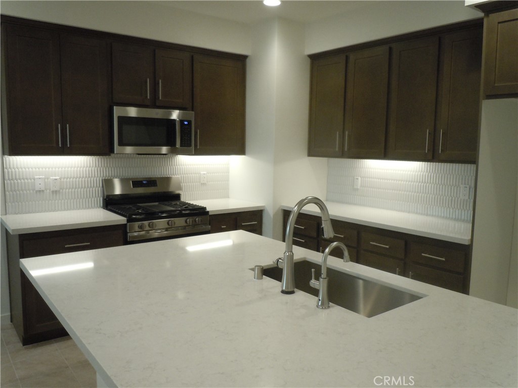 32402 Brunello Way Temecula, CA 92591 - Photo 12 of 22 a kitchen with stainless steel appliances a sink a stove a microwave a sink and cabinets
