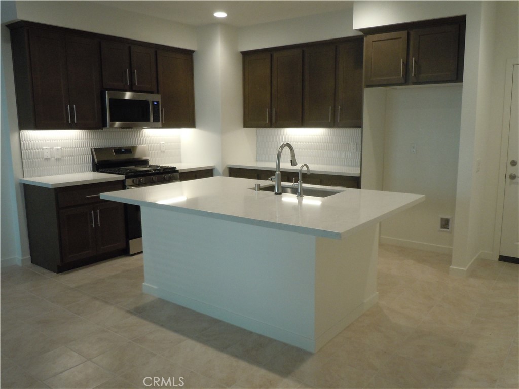 32402 Brunello Way Temecula, CA 92591 - Photo 8 of 22 a kitchen with a sink and a stove with wooden cabinets