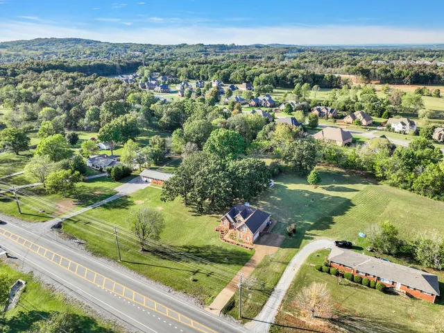 an aerial view of residential houses with outdoor space and trees