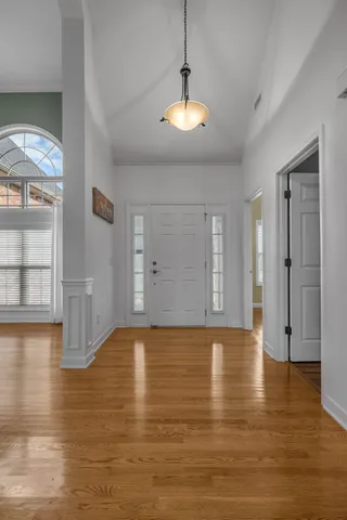 a view of empty room with wooden floor and kitchen
