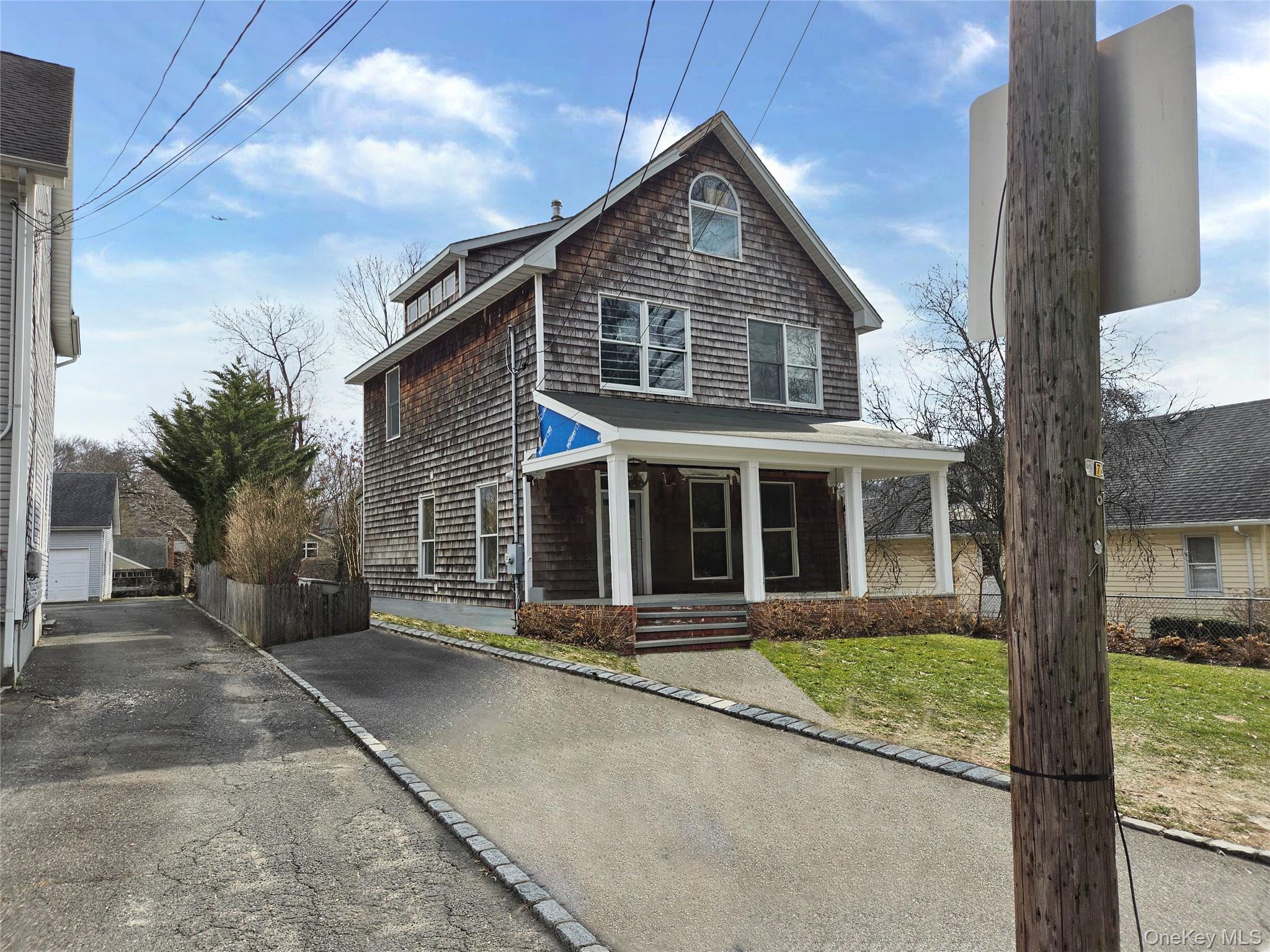 54 Cocks Lane Locust Valley, NY 11560 - Photo 2 of 6 a front view of a house with a garden and trees