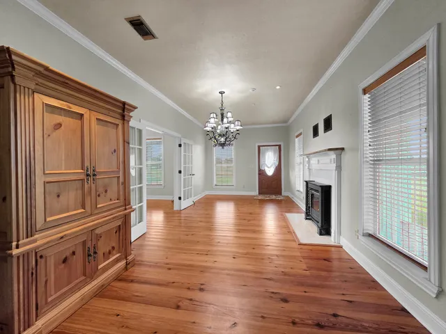 an empty room with wooden floor fireplace and windows