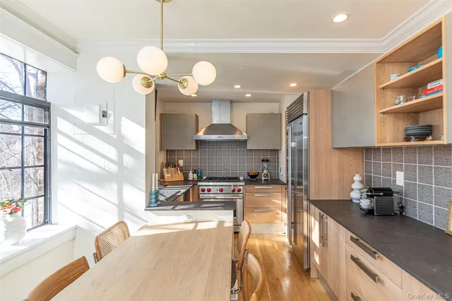 a large kitchen with stainless steel appliances a large counter top a stove and a wooden floors