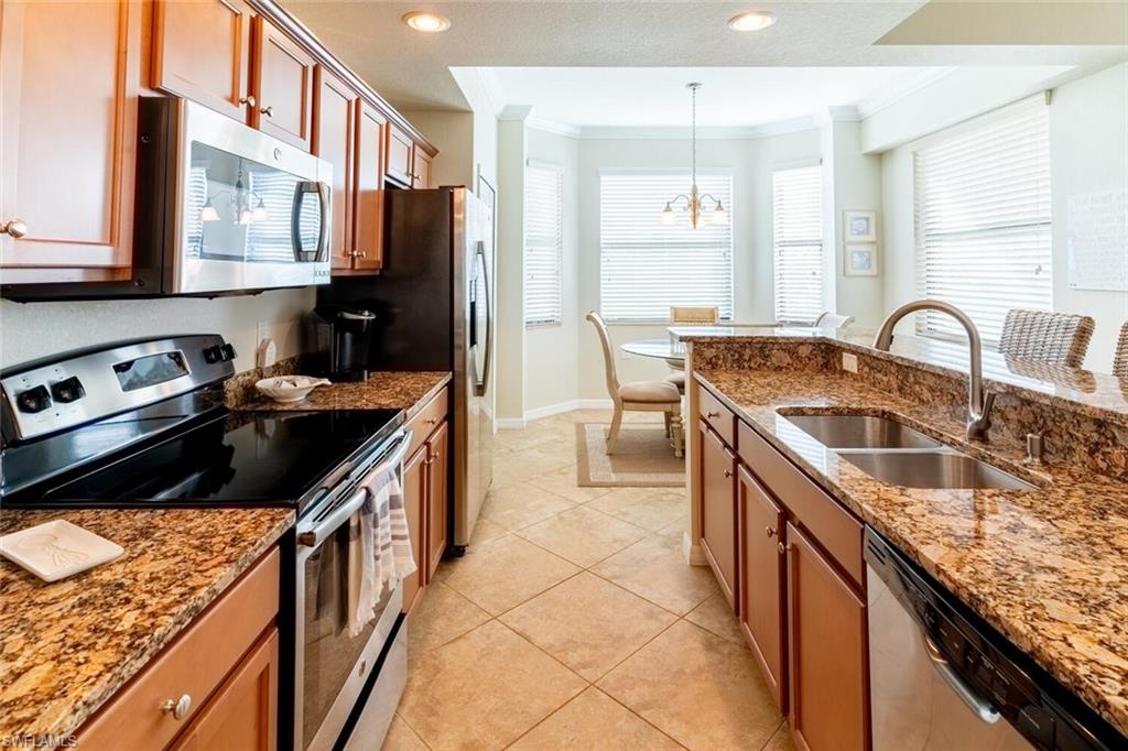 9731 Acqua Court, Unit 536 Naples, FL 34113 - Photo 11 of 48 a kitchen with stainless steel appliances granite countertop a sink stove and refrigerator