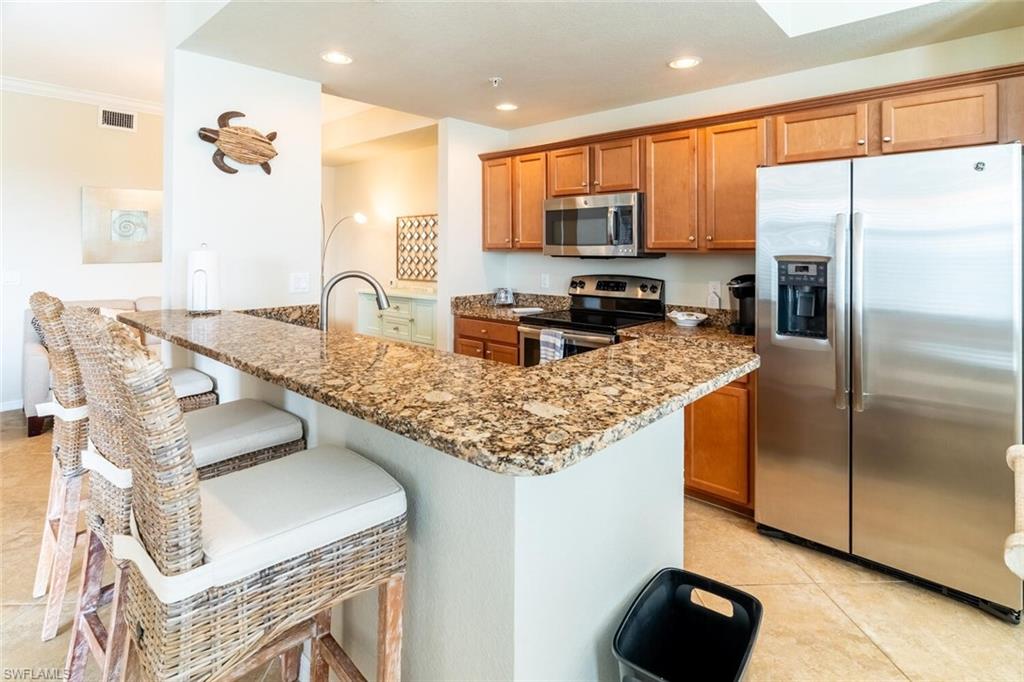 9731 Acqua Court, Unit 536 Naples, FL 34113 - Photo 13 of 48 a kitchen with stainless steel appliances granite countertop a sink refrigerator and microwave