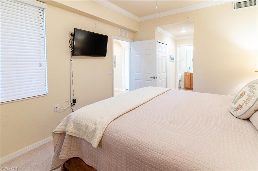 9731 Acqua Court, Unit 536 Naples, FL 34113 - Photo 16 of 48 a bedroom with a bed and a flat screen tv