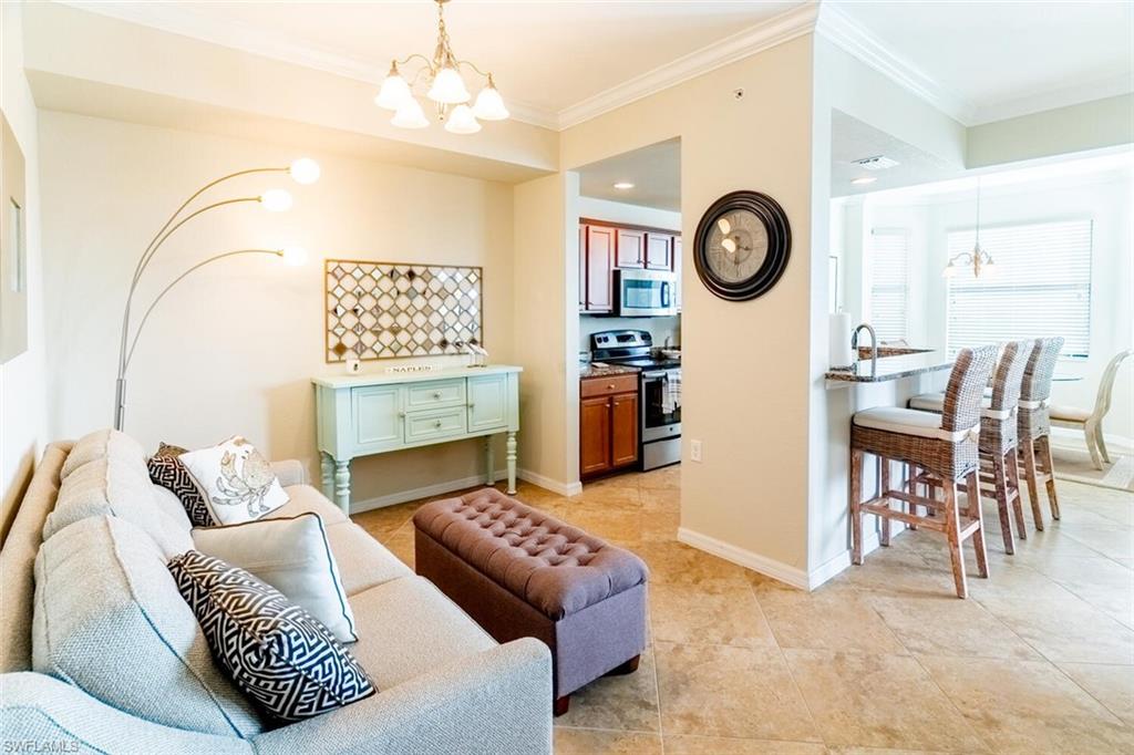 9731 Acqua Court, Unit 536 Naples, FL 34113 - Photo 10 of 48 a living room with furniture a clock on wall and a clock