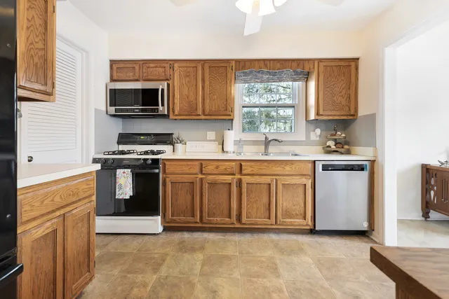 a kitchen with stainless steel appliances granite countertop a stove a sink and a microwave