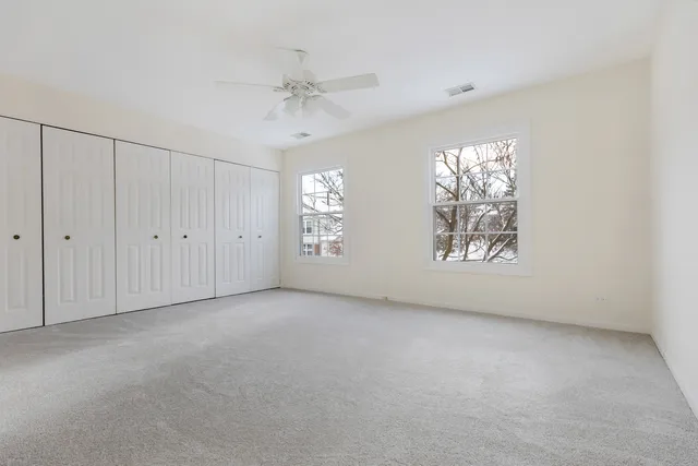 an empty room with windows and chandelier fan