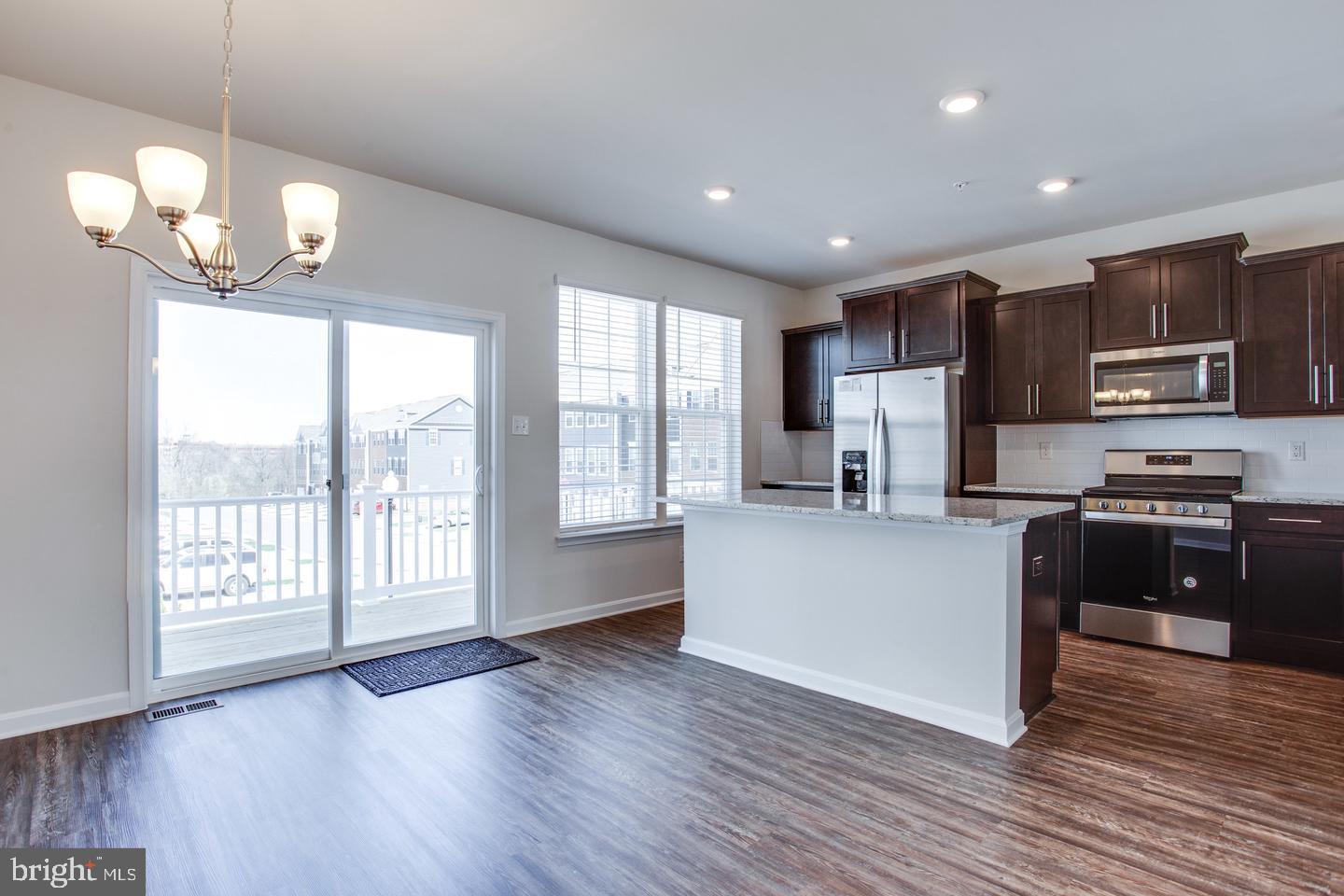 7068 Delegate Place Frederick, MD 21703 - Photo 24 of 76 a kitchen with stainless steel appliances granite countertop a refrigerator a sink dishwasher a kitchen island with wooden floor and cabinets