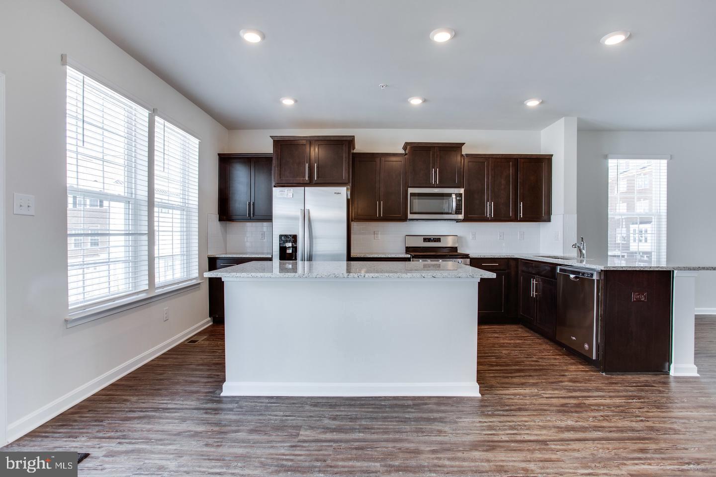 7068 Delegate Place Frederick, MD 21703 - Photo 25 of 76 a large kitchen with stainless steel appliances granite countertop a stove a sink dishwasher a microwave oven and a refrigerator with wooden floor