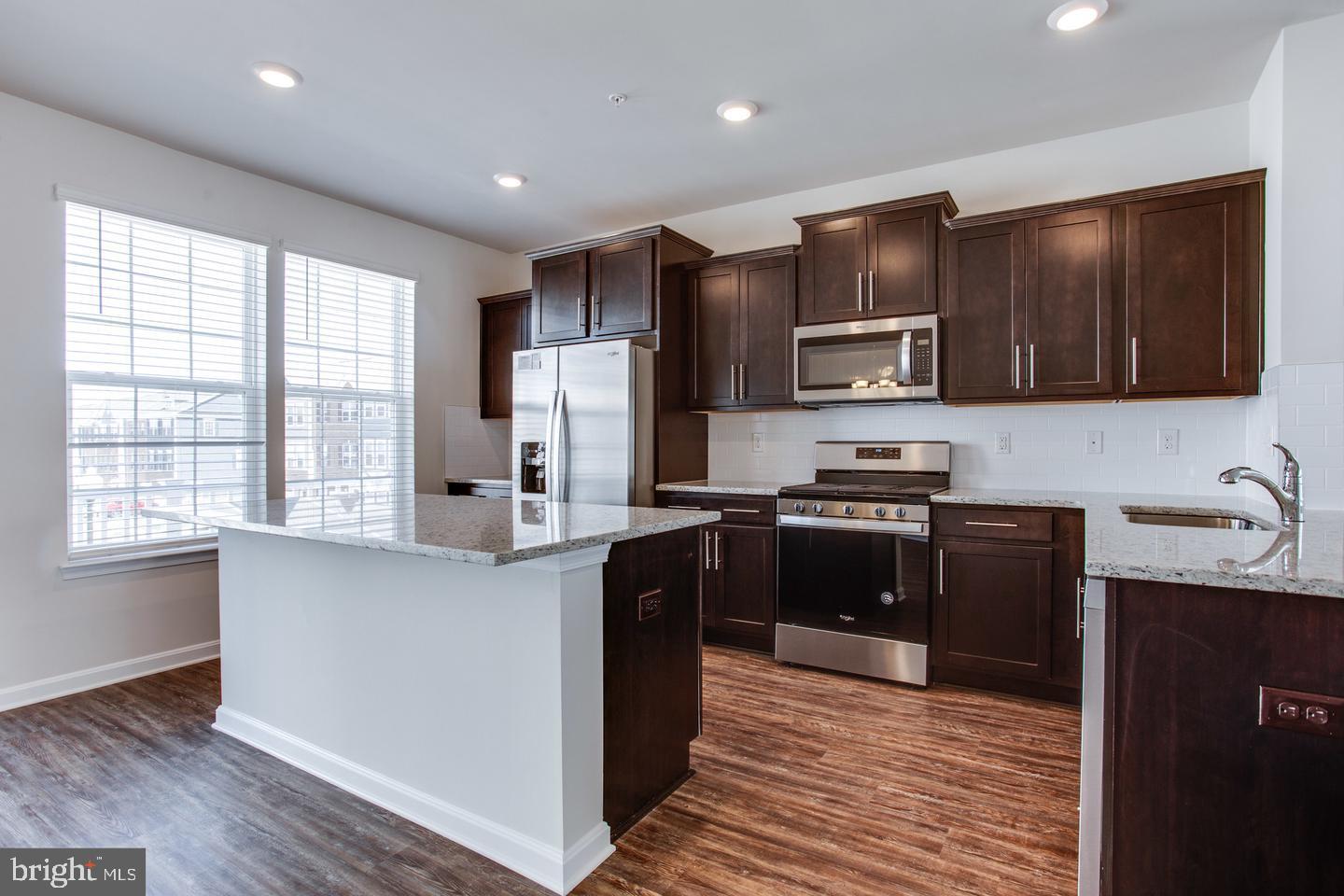 7068 Delegate Place Frederick, MD 21703 - Photo 26 of 76 a kitchen with granite countertop wooden cabinets a stove a refrigerator and a microwave oven with wooden floor