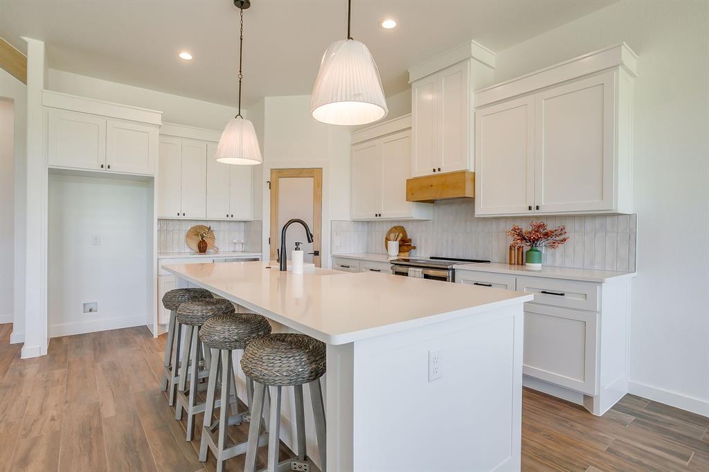 9012 Valley Oak Court Springtown, TX 76082 - Photo 14 of 40 a kitchen with stainless steel appliances granite countertop a sink a stove a refrigerator and island with wooden floor