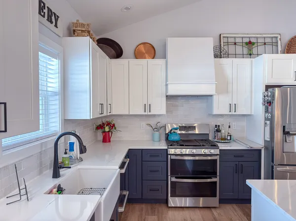 a kitchen with stainless steel appliances granite countertop a stove a sink and a white cabinets