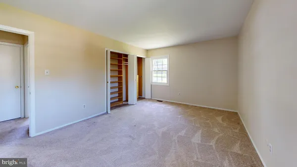 an empty room with closet and windows