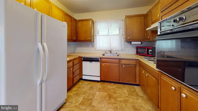 a kitchen with stainless steel appliances granite countertop a refrigerator a stove top oven a sink and dishwasher