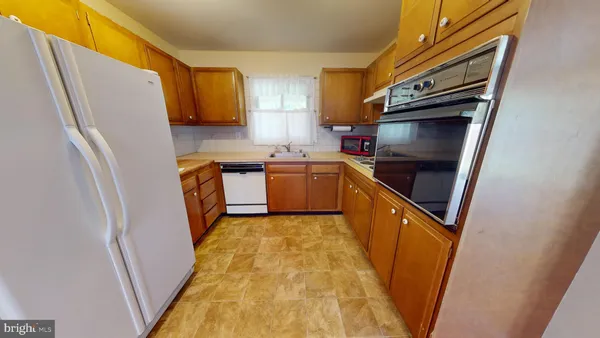 a kitchen with stainless steel appliances a refrigerator a sink and wooden cabinets