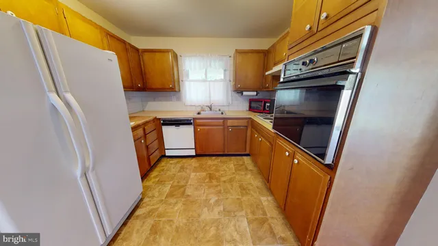 a kitchen with stainless steel appliances a refrigerator a sink and wooden cabinets