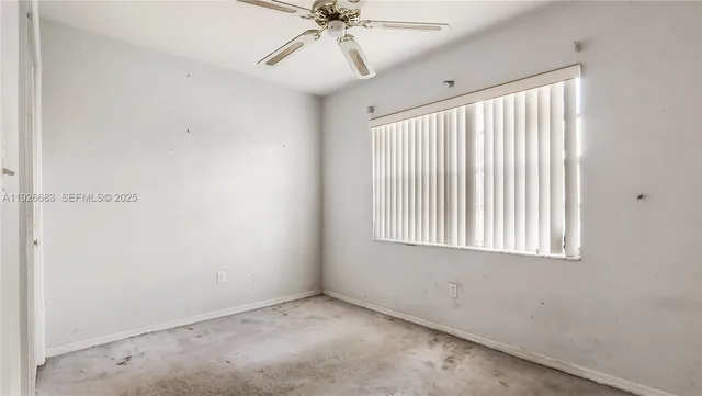 an empty room with a window and a fan