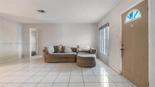 a living room with furniture and a refrigerator