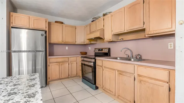 a kitchen with granite countertop a refrigerator sink and cabinets