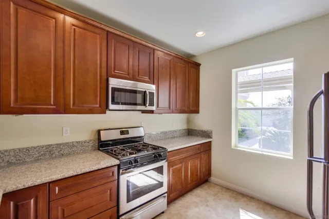 a kitchen with granite countertop wooden cabinets stainless steel appliances and a window