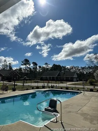 a view of a swimming pool with lawn chairs and plants