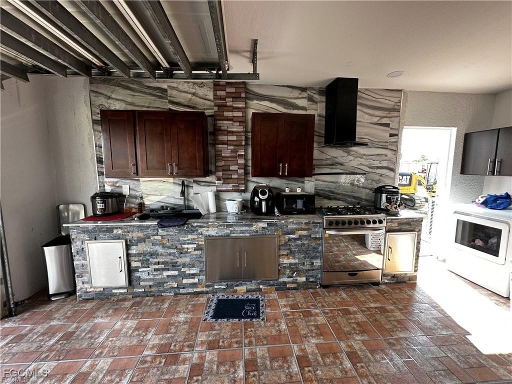 3315 37th Street Southwest Lehigh Acres, FL 33976 - Photo 13 of 34 a kitchen with kitchen island granite countertop a stove top oven a sink a counter space and cabinets