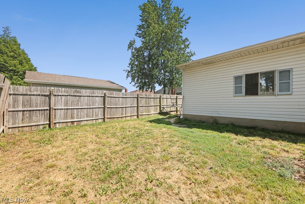 611 Herbert Road Akron, OH 44312 - Photo 7 of 30 Expansive backyard featuring a wood privacy fence, a detached structure with white siding, and a window with exterior shutters