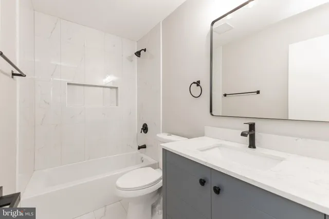 a bathroom with a sink a toilet a mirror a bathtub and shower