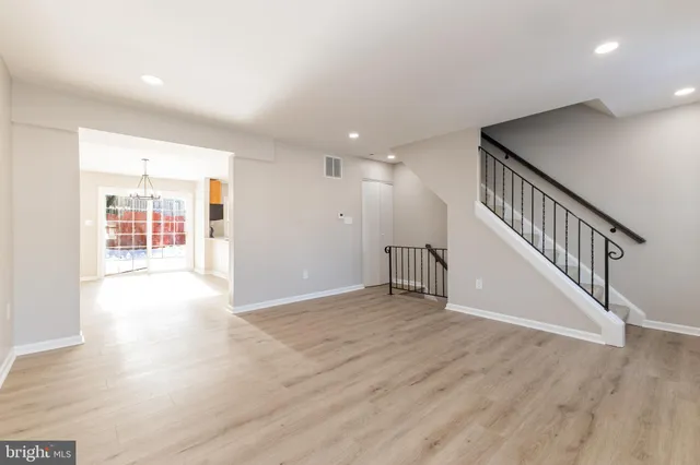 a view of an empty room with wooden floor and stairs
