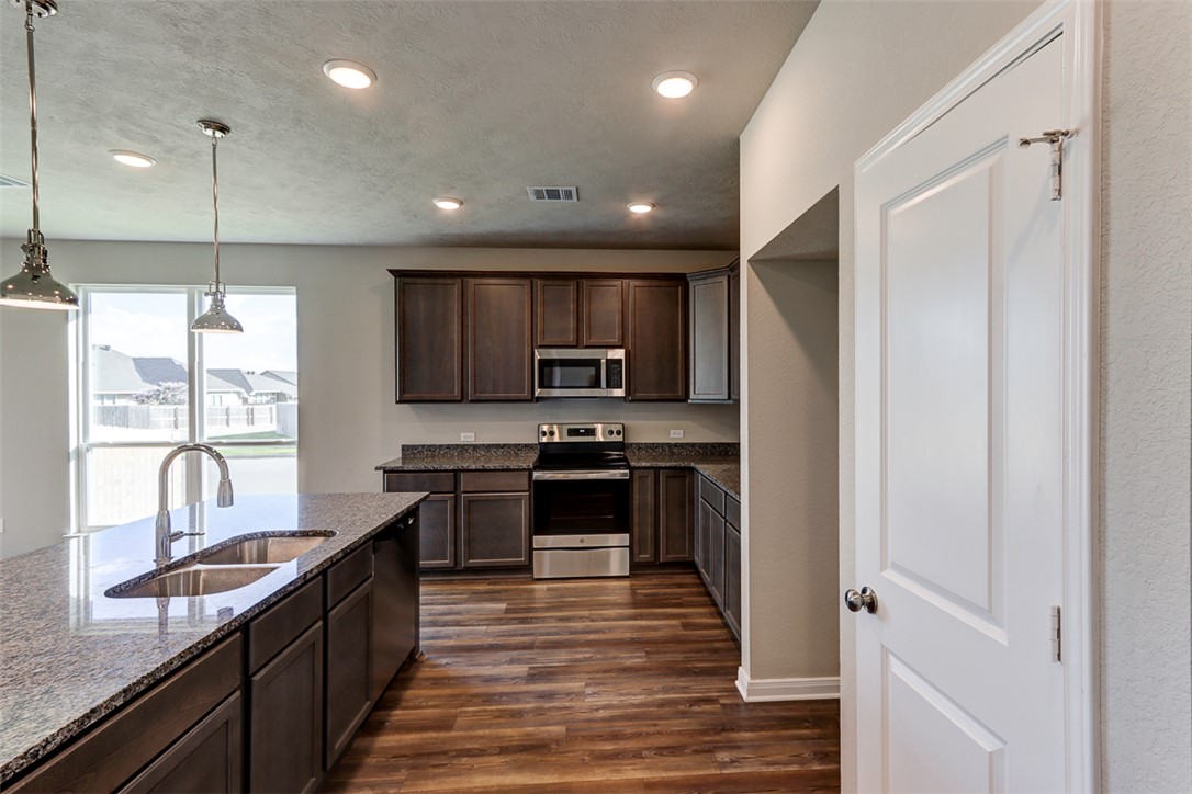 1937 Viva Road Bryan, TX 77807 - Photo 5 of 25 a kitchen with stainless steel appliances granite countertop a refrigerator a sink dishwasher a stove and white countertops with wooden floor